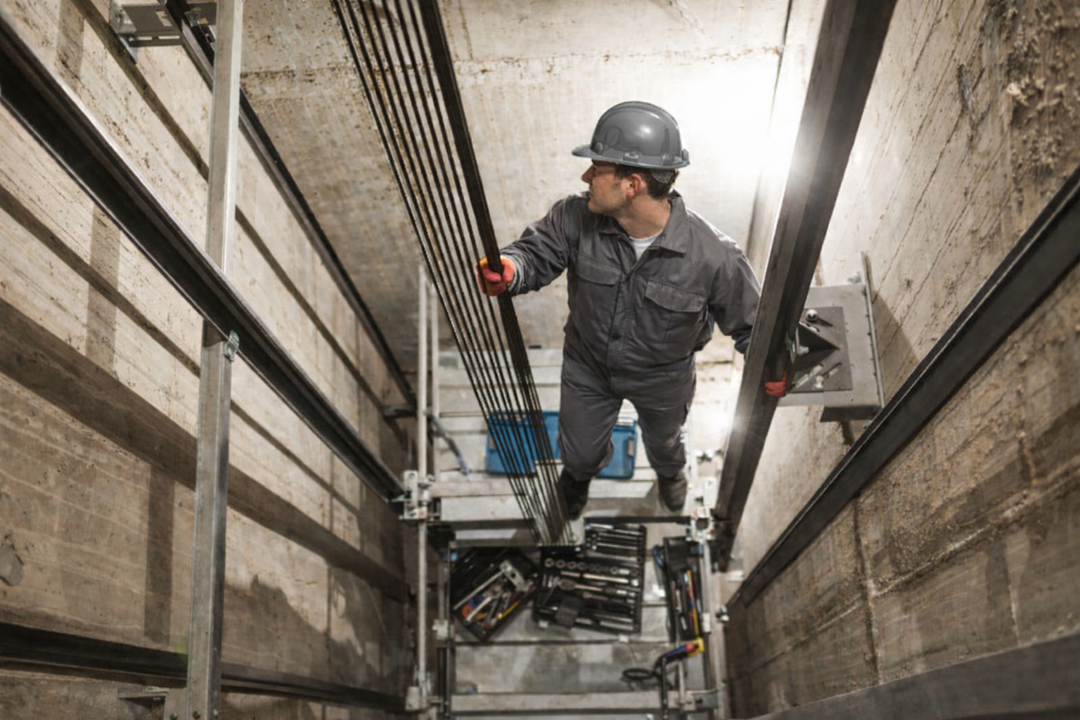 Elevator Mechanic in an Elevator Shaft Repairing an Elevator