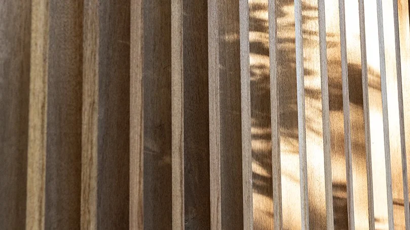 Close-up view of wooden slats and metal bars, sunlight casting shadows