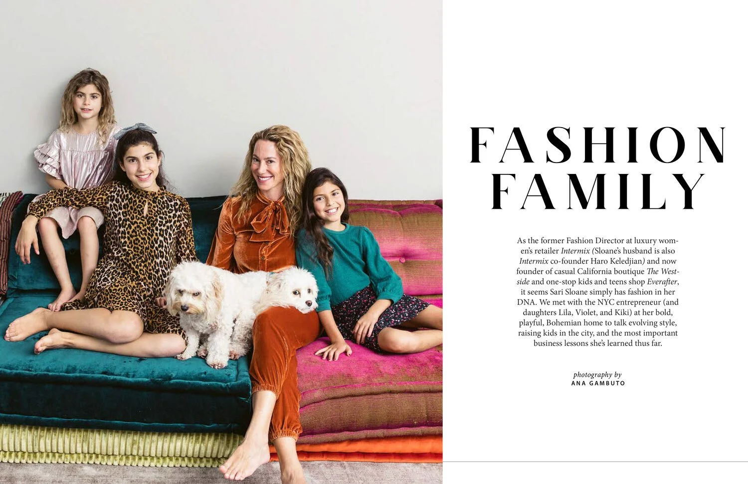 Family of five with two dogs sitting on a colorful sofa, smiling at the camera.