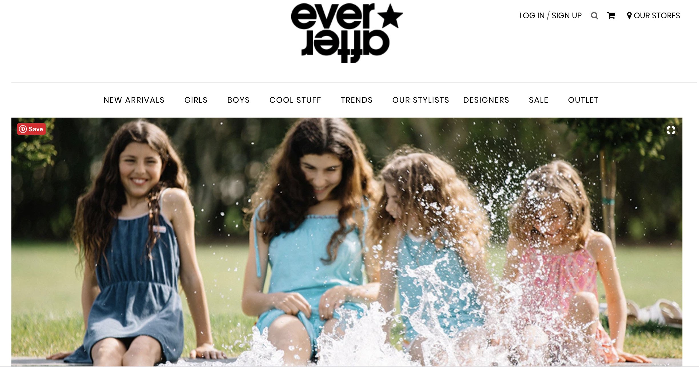 Four girls sitting on grass and playing in water outdoors, smiling and splashing