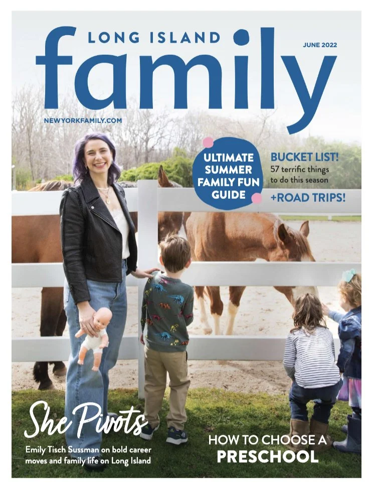 Cover of Long Island Family magazine, June 2022 issue, featuring a woman with purple hair holding a baby doll posing outdoors near a white fence with horses and children in the background.