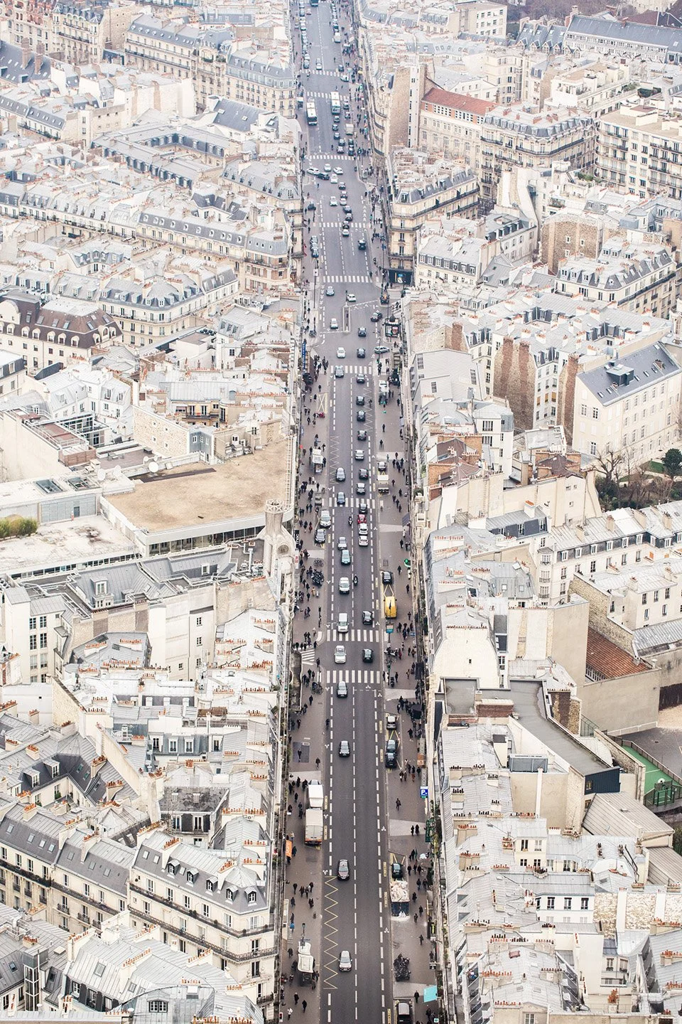 Aerial view of a city street with cars, pedestrians, and buildings on both sides.