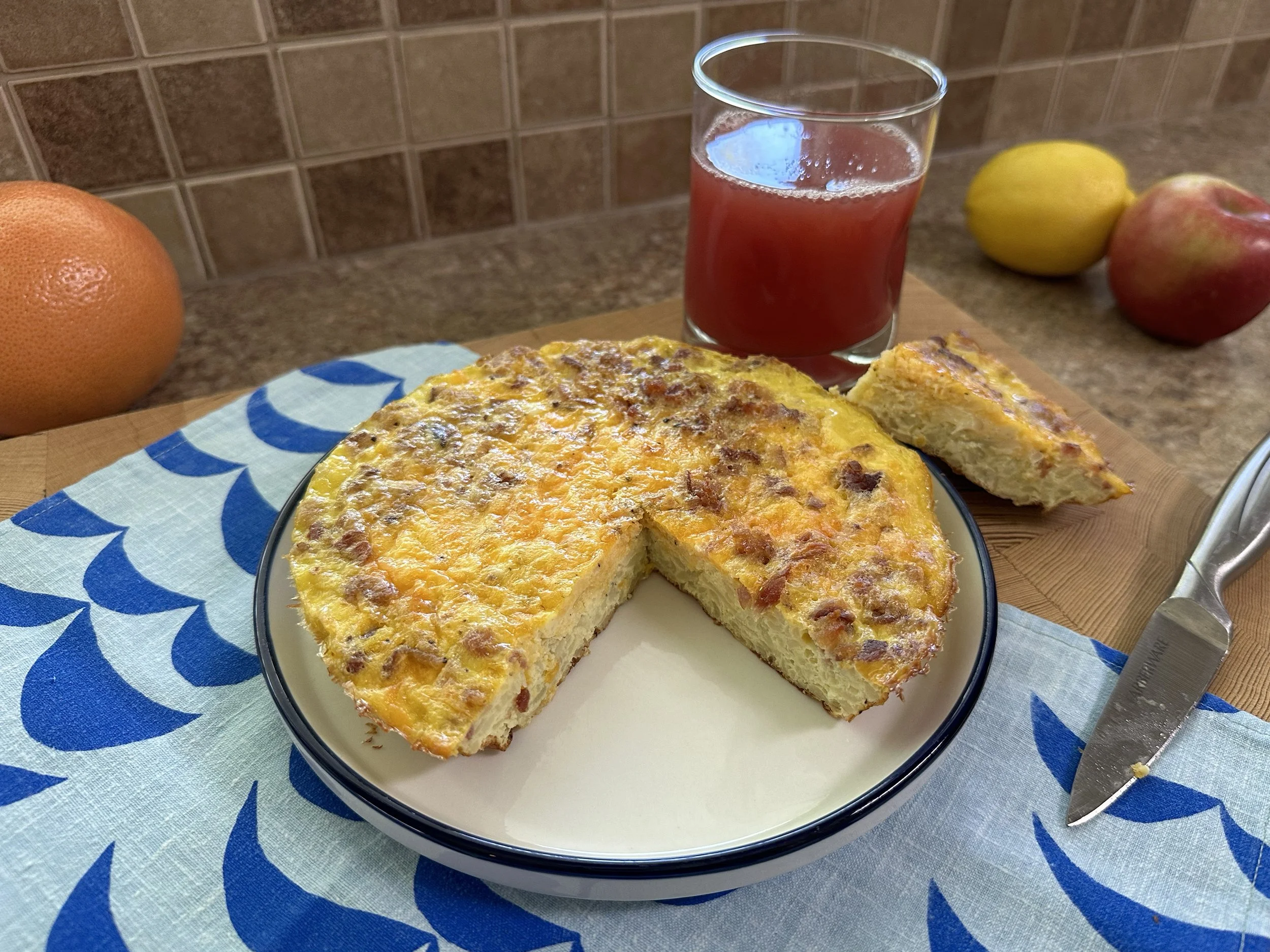 Breakfast egg casserole with a cup of cranberry juice in the background