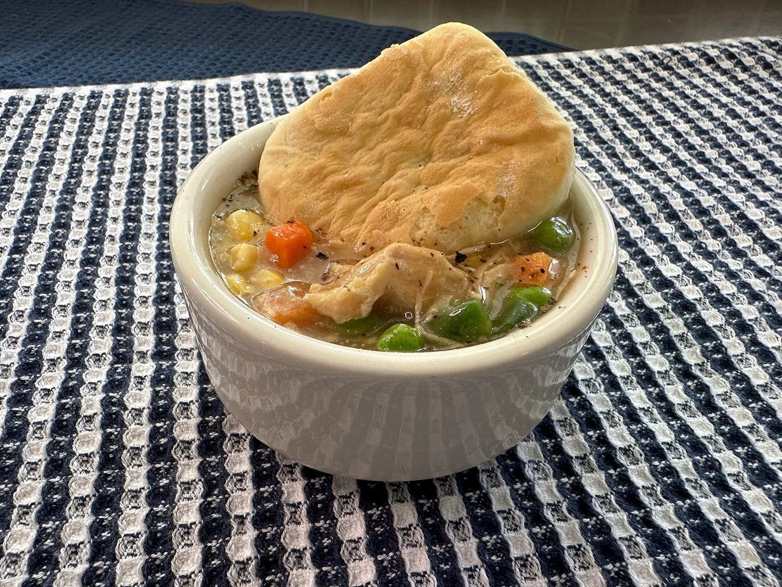 A bowl of chicken and gravy with a biscuit on top, inspired by chicken pot pie