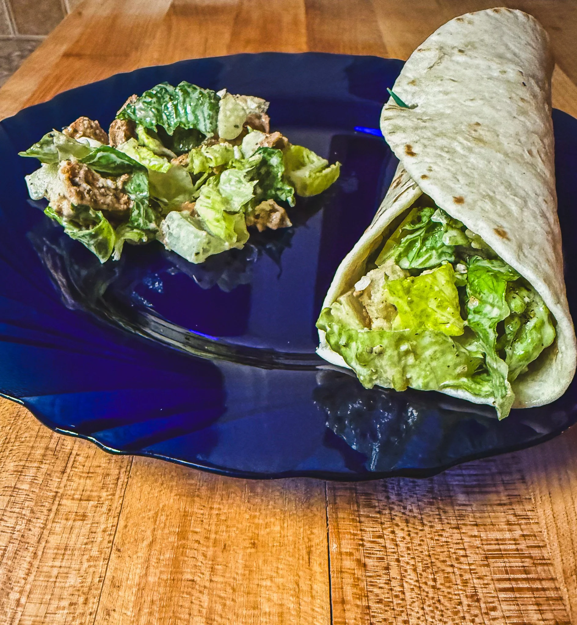 The Jimmy Caesar Wrap from Boki's Kitchen on a navy blue plate.