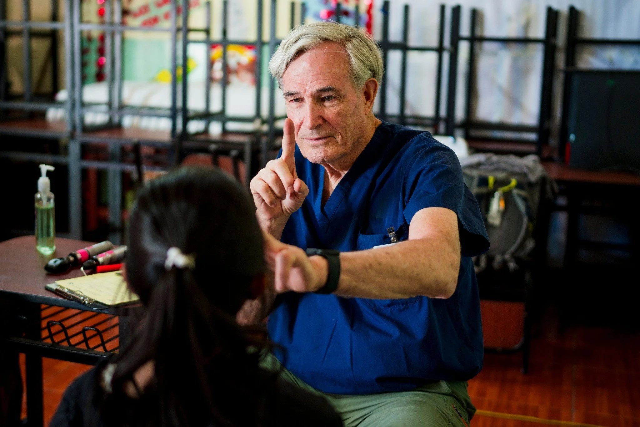 Four smiling women, including an elderly woman wearing a witch hat and sitting in the middle, gathered together for a group photo.