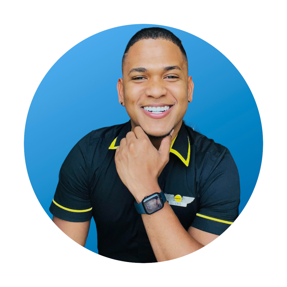 Smiling man wearing a black uniform with yellow accents, a name tag that says 'Cris', and a smartwatch, posing against a blue background.