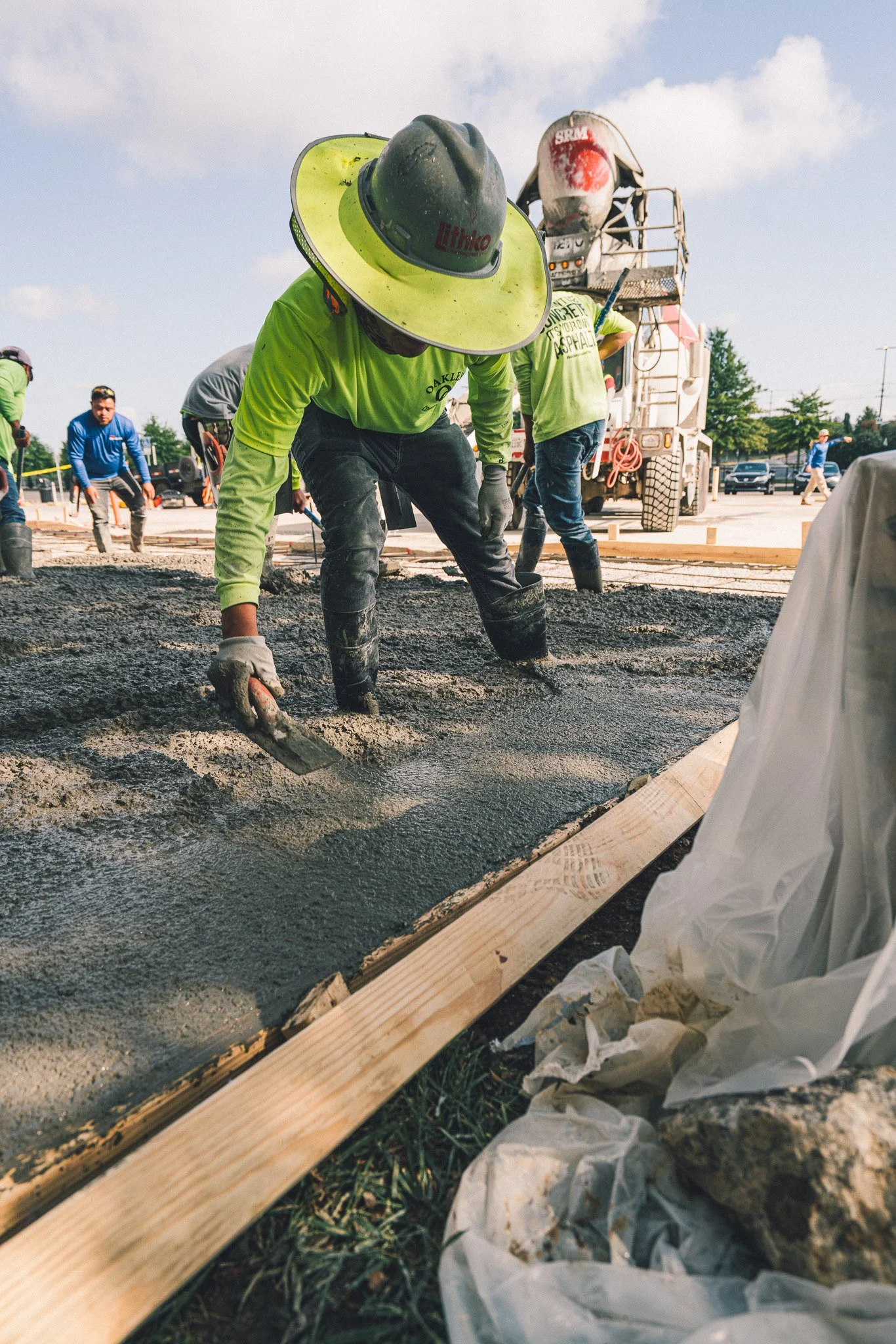 Construction workers pouring and smoothing concrete on a construction site.