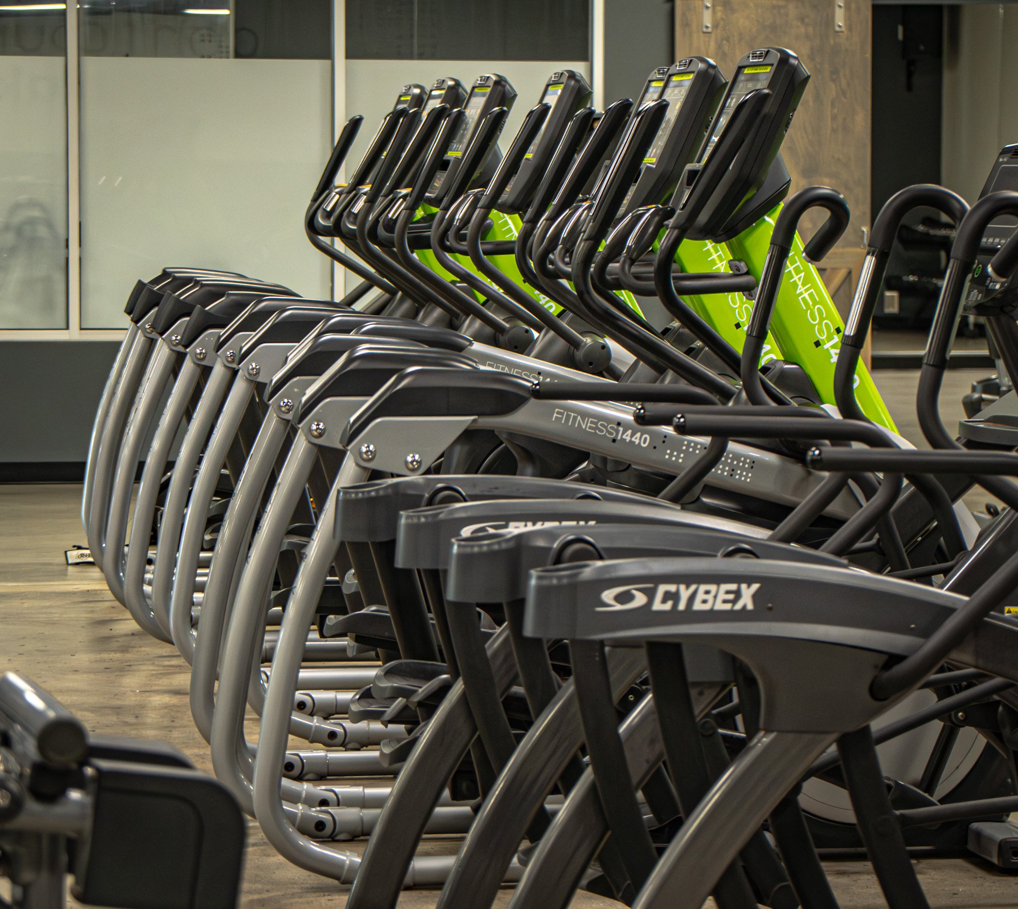 Row of exercise bikes in a gym, with black and green bikes in the background.