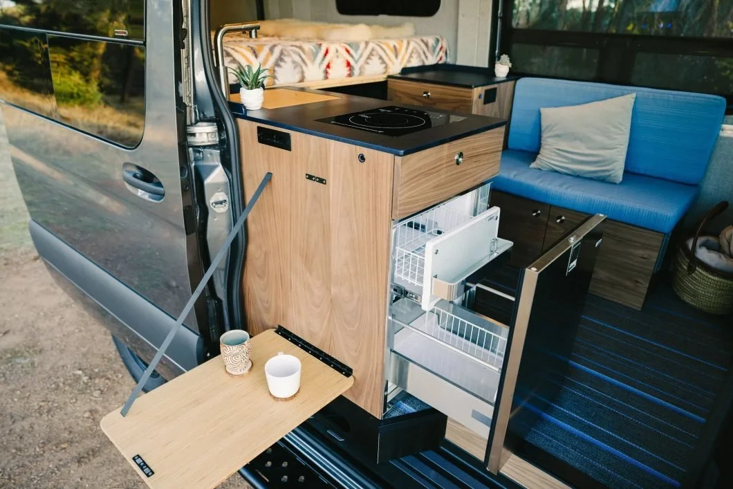 A sprinter van showing a customized wood pullout table for an adventure sprinter van