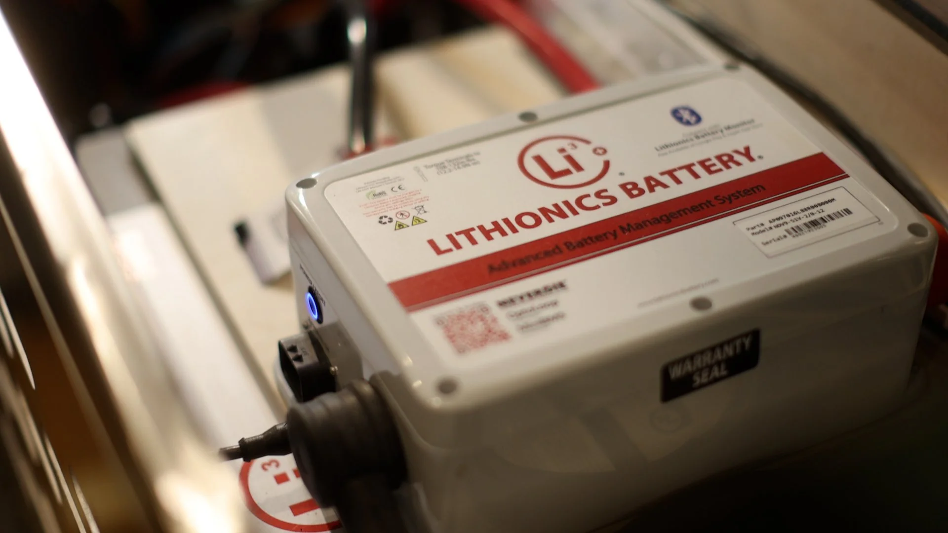 Close-up of a Lithium-ion battery labeled 'Lithionics Battery' on a battery management system, connected to a device with visible wiring.