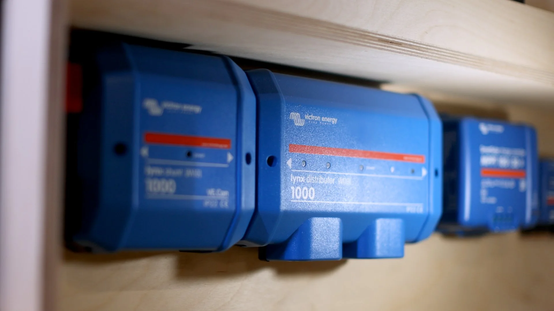 Close-up of blue electrical switchgear with white text and red indicators mounted on a wooden surface.