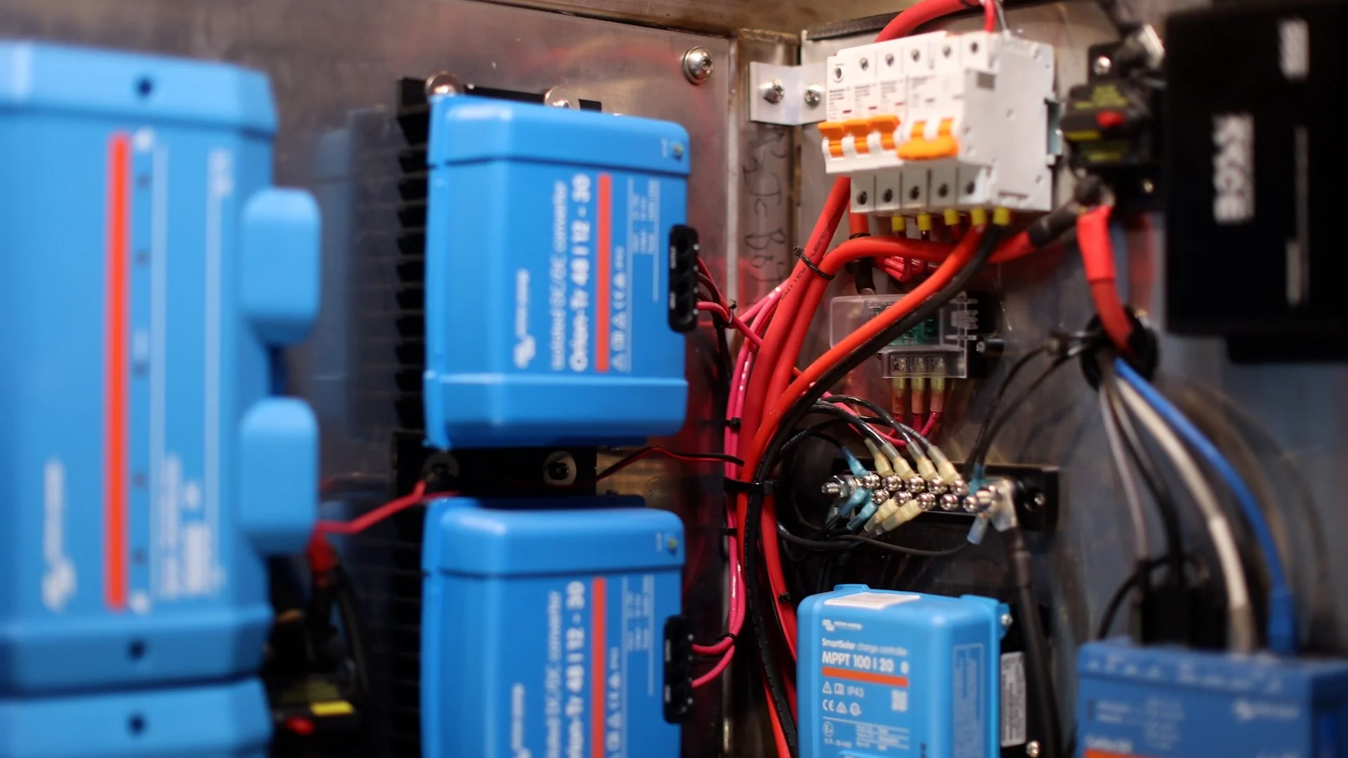 Electrical panel with various blue, red, black, and white wires, circuit breakers, and circuit modules.