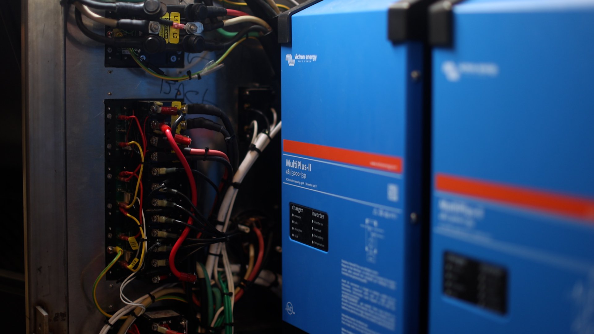 Close-up of an industrial electrical panel with colorful wiring and a large blue Victron Energy MultiPlus-II inverter.