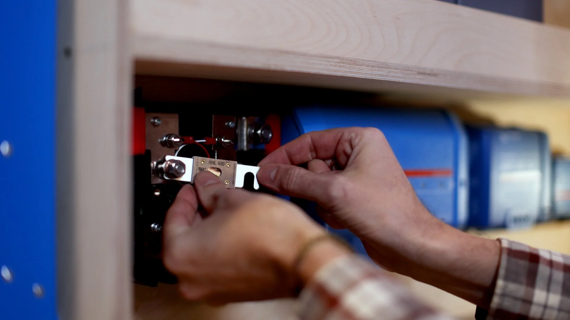 A person working on electrical wiring inside a control panel, adjusting connections with tools.