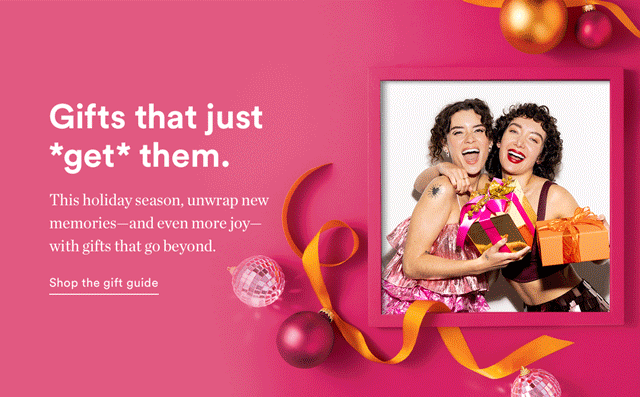 Two women smiling and holding wrapped gift boxes, surrounded by Christmas ornaments and ribbons, against a pink background.