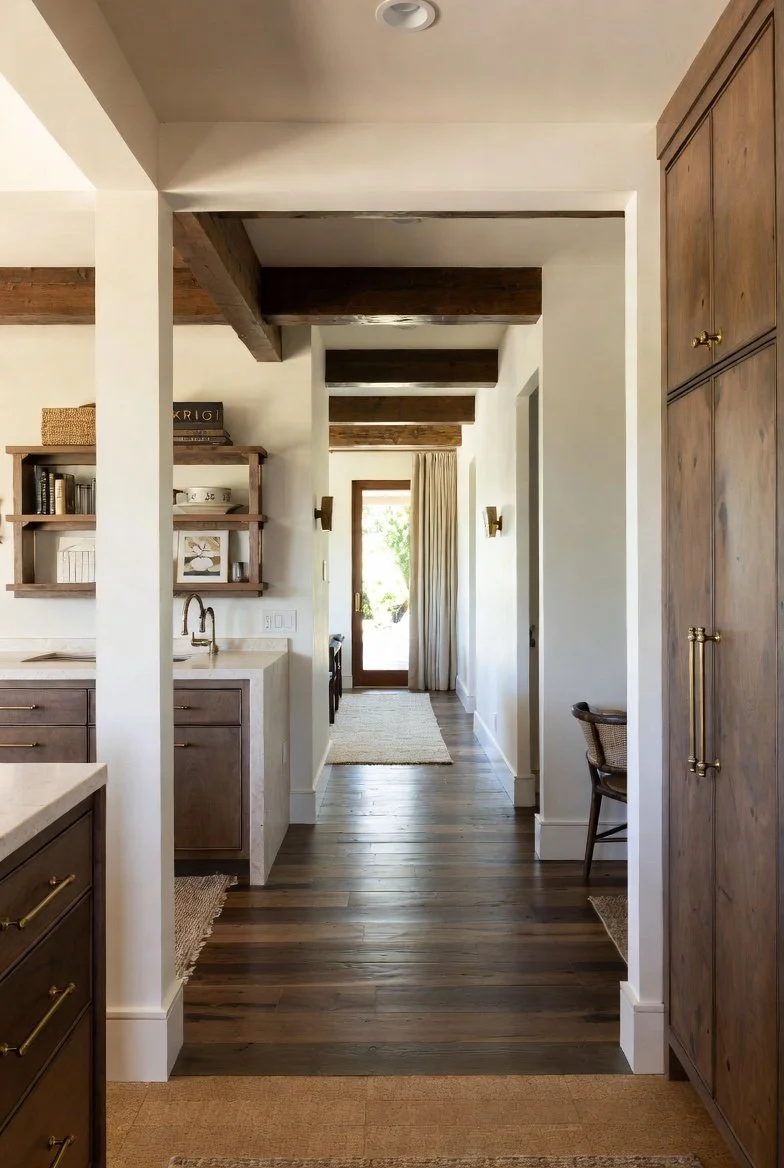 Open-plan luxury living space featuring exposed reclaimed timber vaulted ceiling, wide-plank hardwood floors, layered natural textiles including wool rugs, and matte brass accents for aesthetic and acoustic synergy.