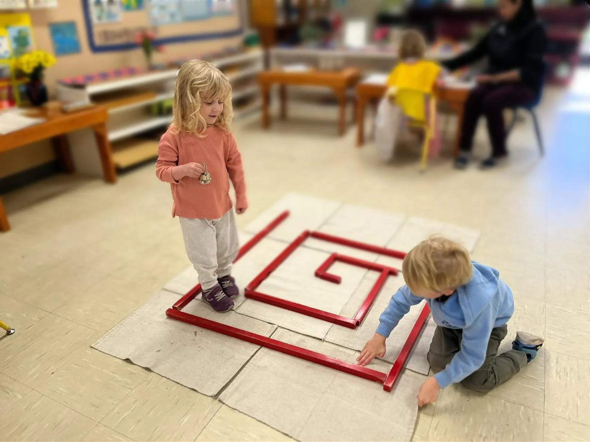 Montessori preschool children engaging in a red rod maze, developing balance, coordination, and problem-solving in an Austin preschool classroom