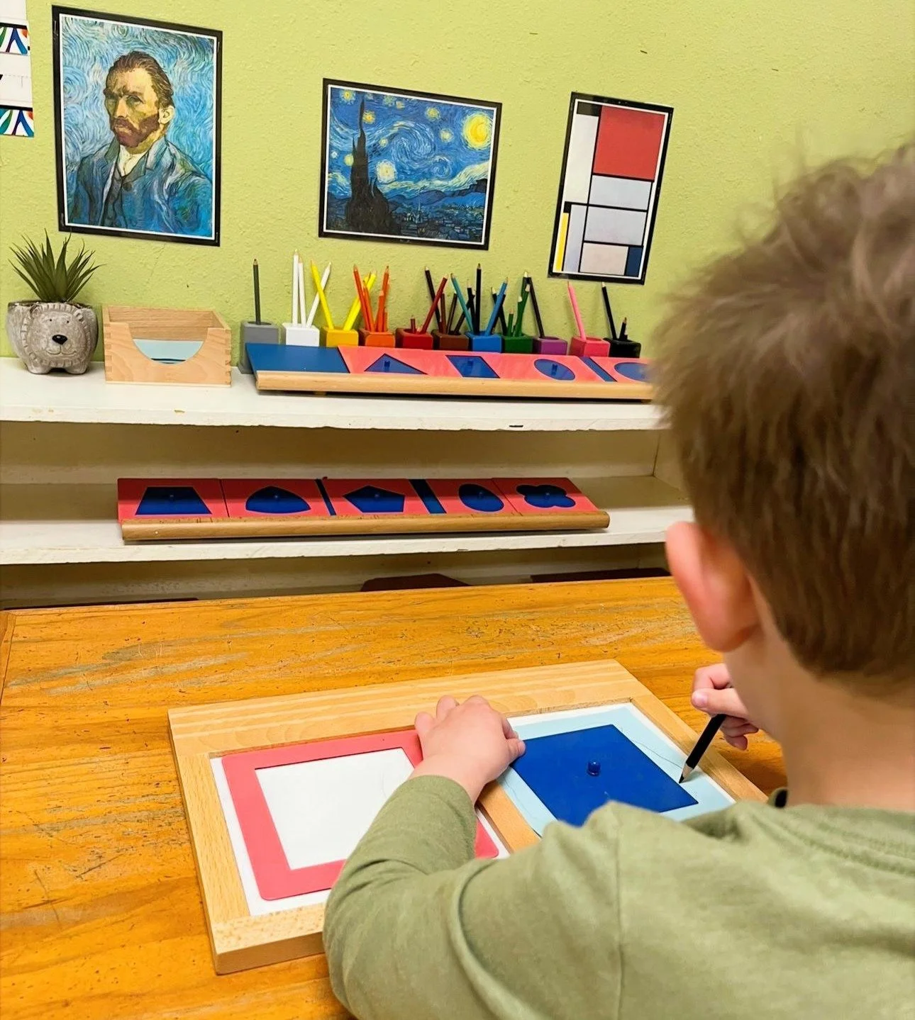 Montessori School student using metal inset tracing work to develop fine motor skills and pencil control in a prepared classroom environment at a South Austin Montessori school
