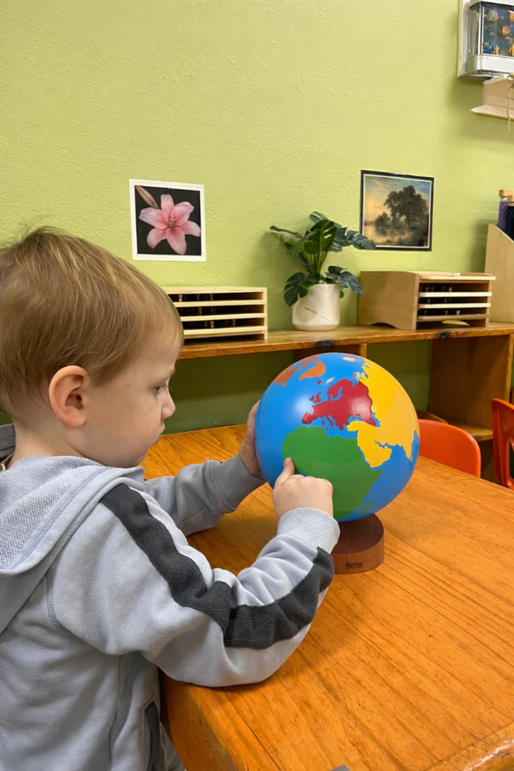 Toddler working with Montessori globe material during early childhood geography lesson at a Montessori school in Austin, Texas.