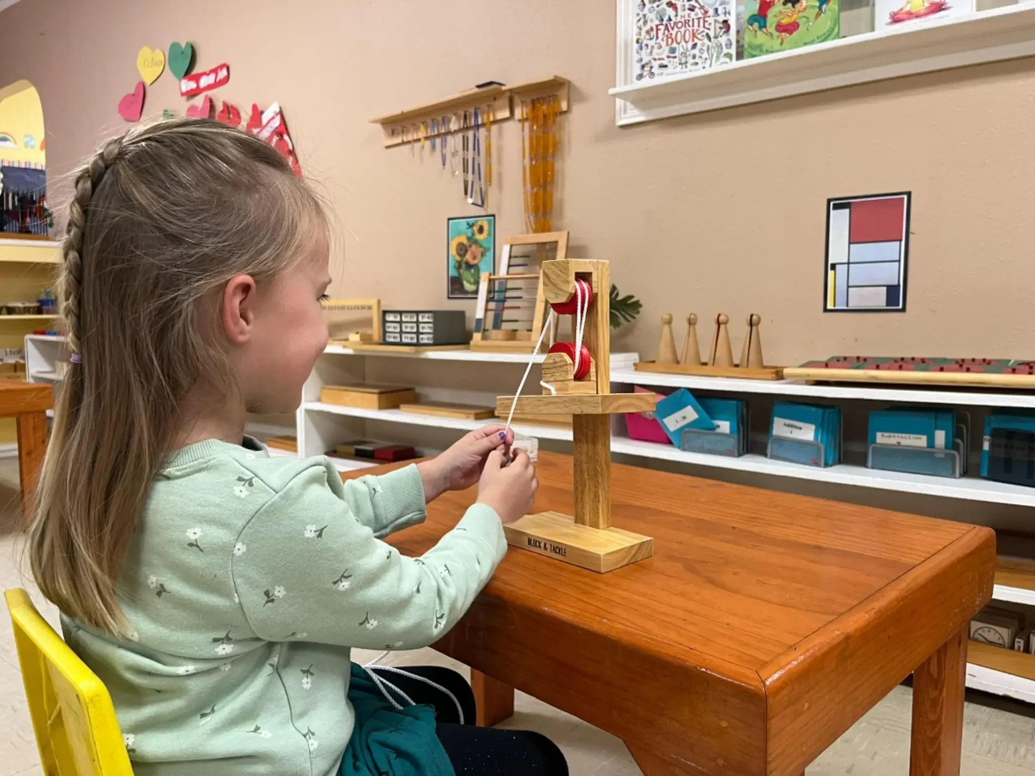 Montessori kindergarten student engaging in hands-on STEM learning with a pulley system at Town & Country Children's Montessori in South Austin