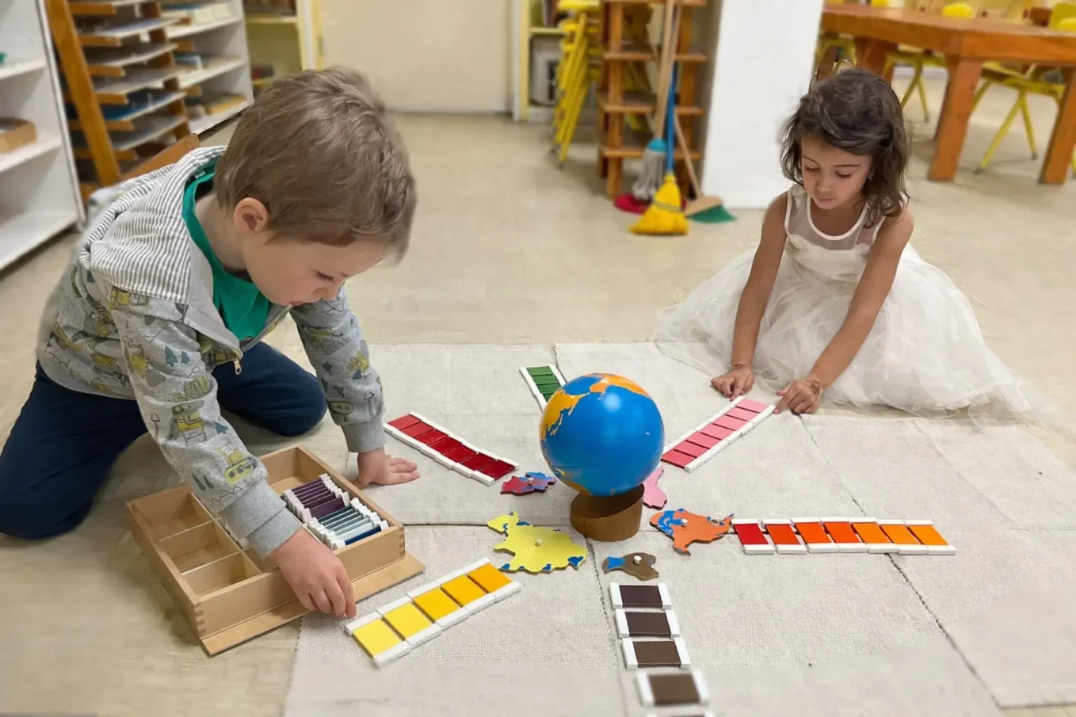 Preschool children exploring Montessori geography globe and color tablets in South Austin, Texas