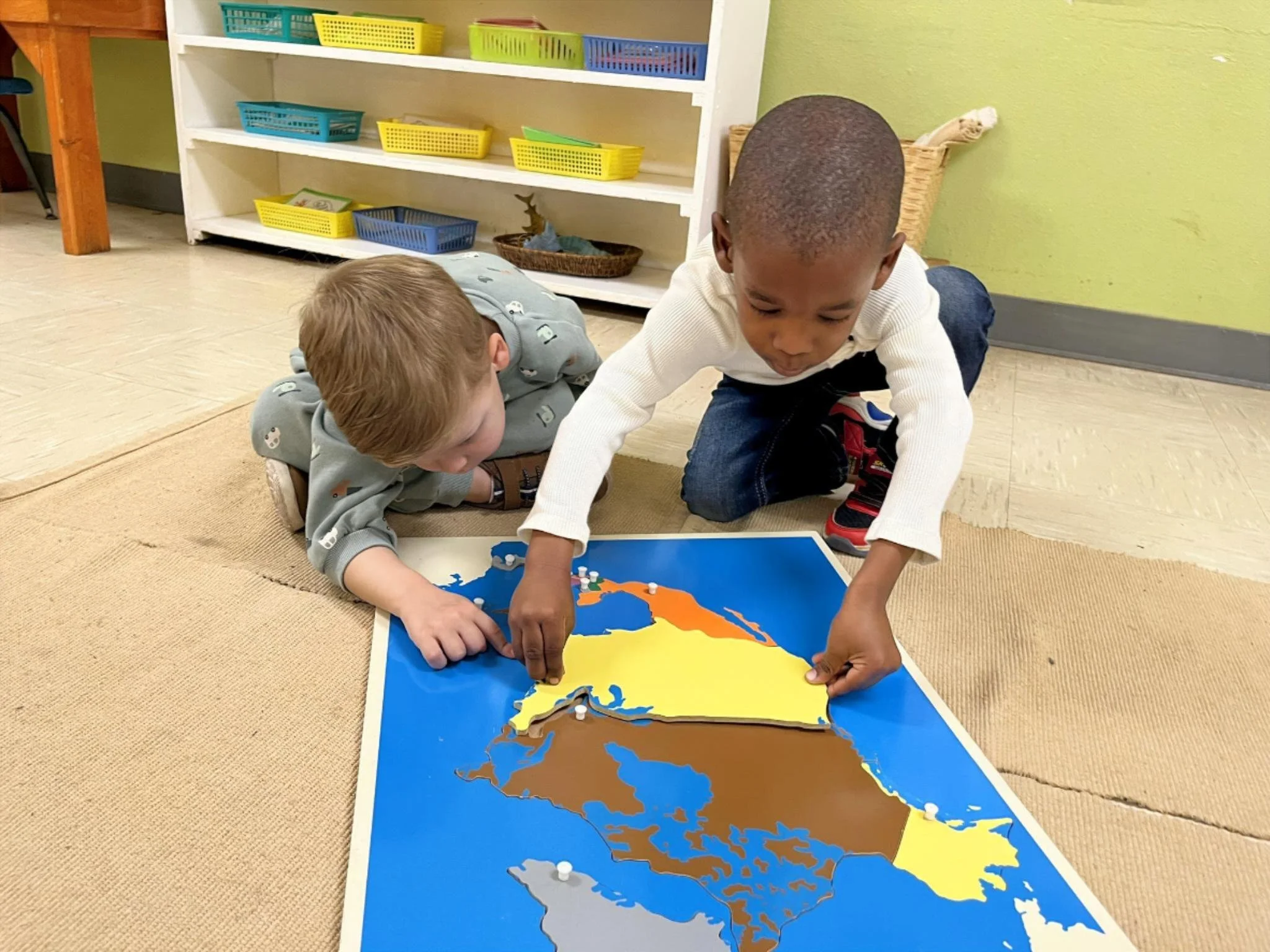 Primary children exploring Montessori geography materials at Town & Country Montessori in Austin, TX