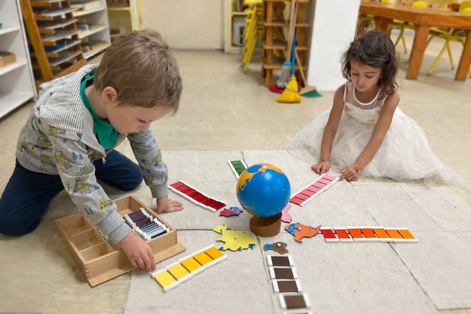 Preschool children exploring Montessori geography globe and color tablets in South Austin, Texas