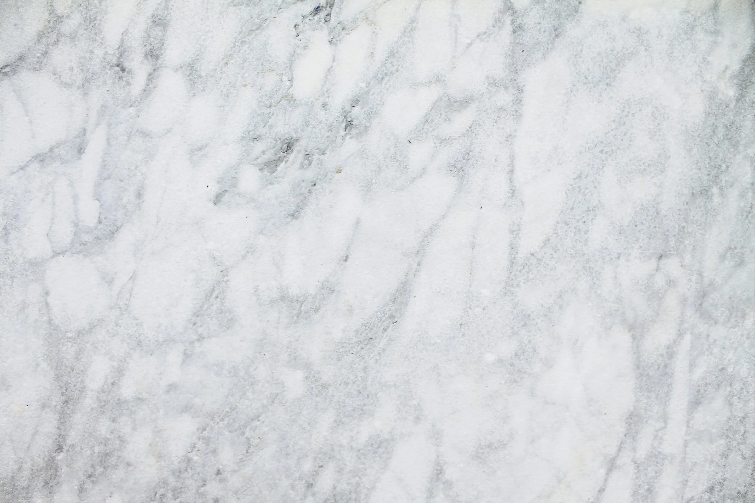 White marble surface with soft, flowing gray veining running diagonally across the stone.