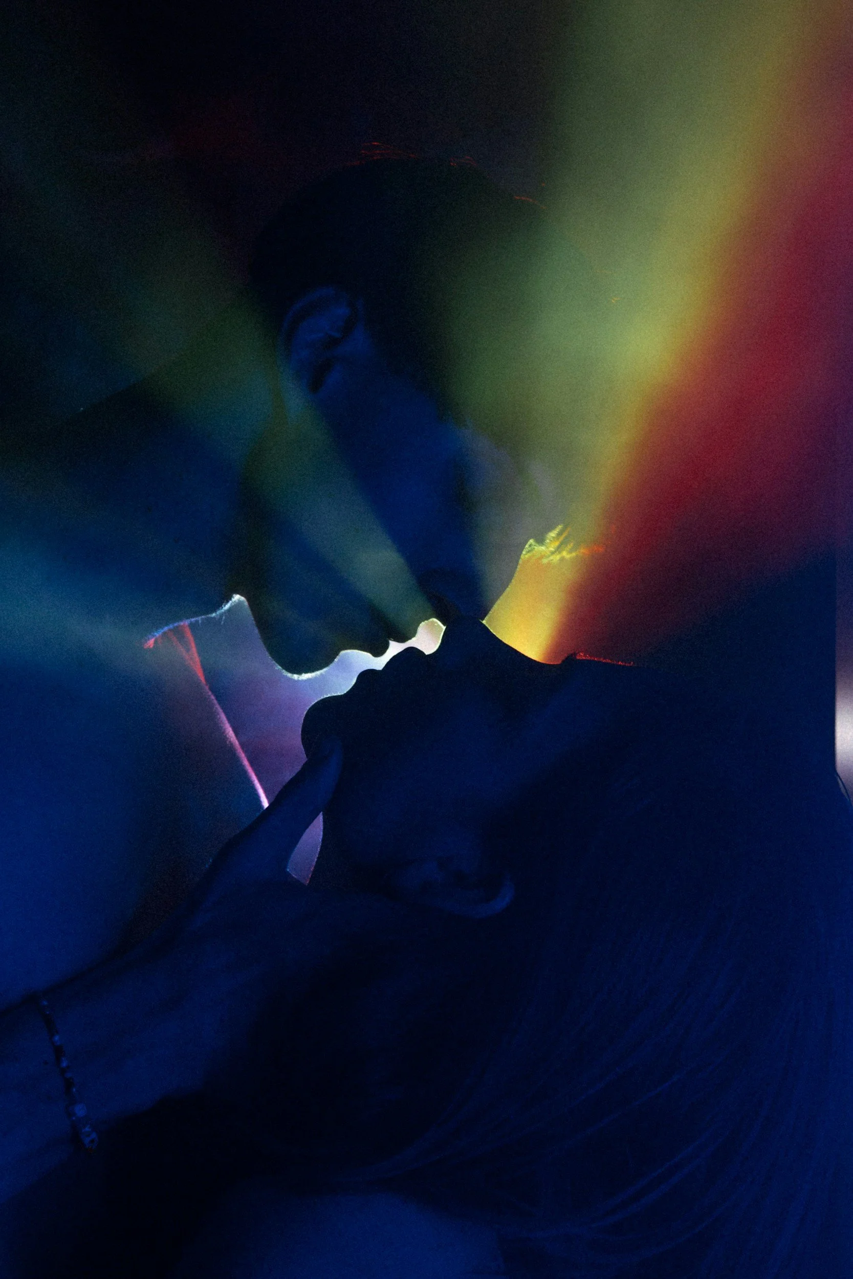 A silhouette of a couple in an intimate pose with colorful light effects in the background, creating a dramatic and romantic atmosphere.