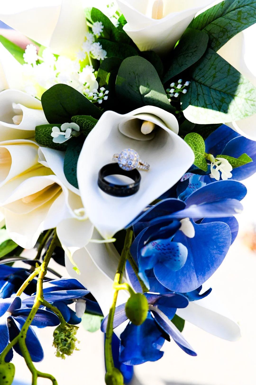Close-up of a bouquet of white and blue flowers with rings placed on a white flower
