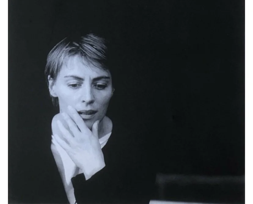 Black and white portrait of an actress in rehearsal with short hair, resting her chin on her hand, looking contemplative.