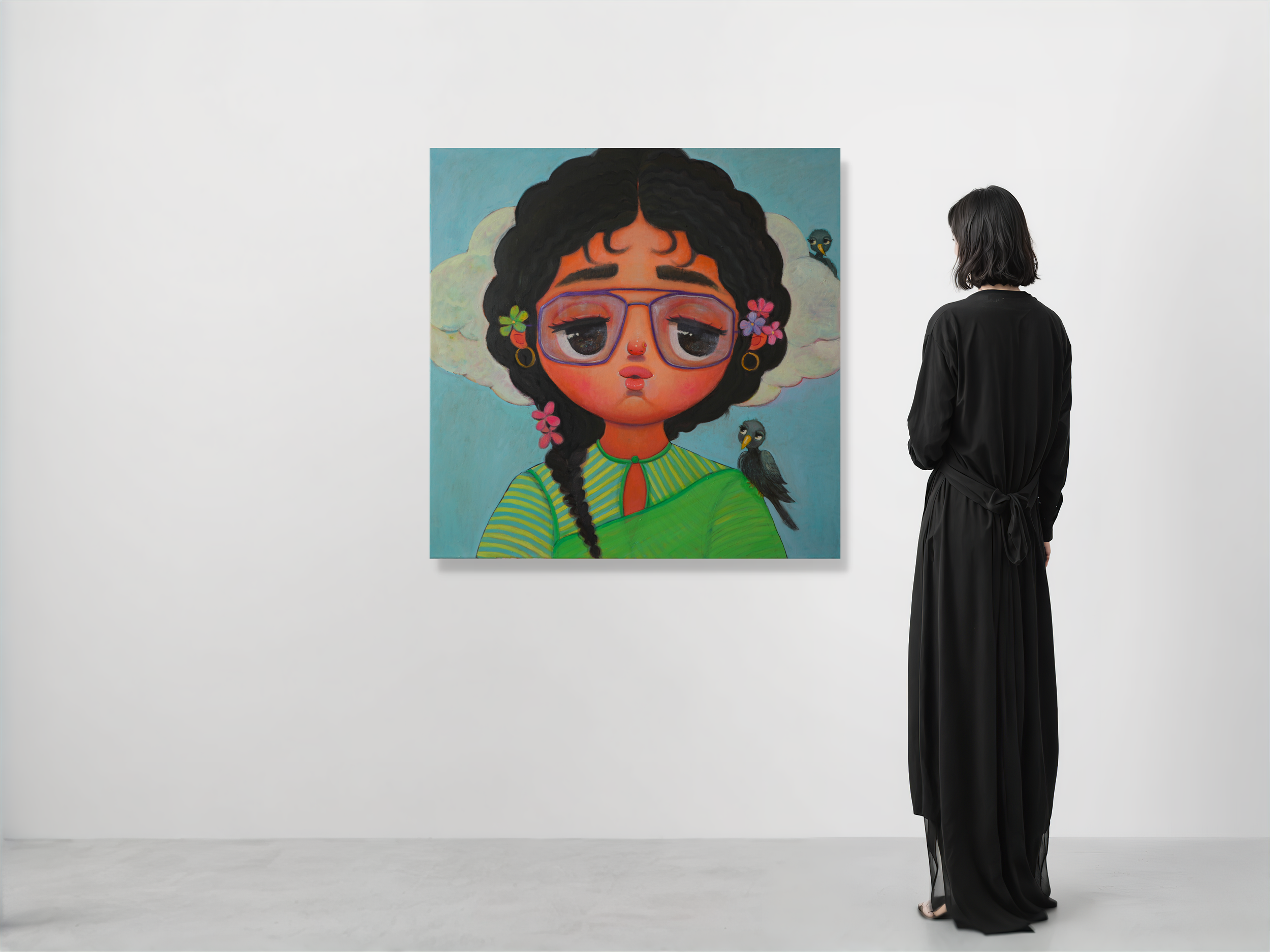 A person with shoulder-length black hair, wearing a long black dress, stands in an art gallery, facing a large colorful painting of a woman with curly black hair, glasses, and flowers, with birds sitting on her shoulders.