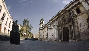 Exterior of the former Convent of San Jerónimo in Mexico City with the modern statue of Sor Juana Inés de la Cruz in the foreground.