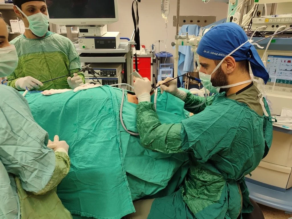 Ameliyat yapan doktorlar ve sağlık ekipleri, ameliyat masasındaki hastanın üzerine kalın yeşil ameliyat örtüsü serilmiş.