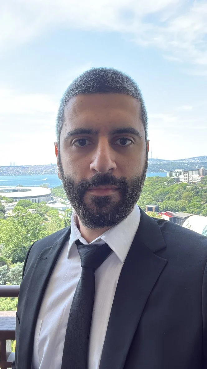 Kadın, gökyüzü manzaralı, şehir ve doğa iç içe, şık kıyafetli, gülümsemeyen bir pozda.