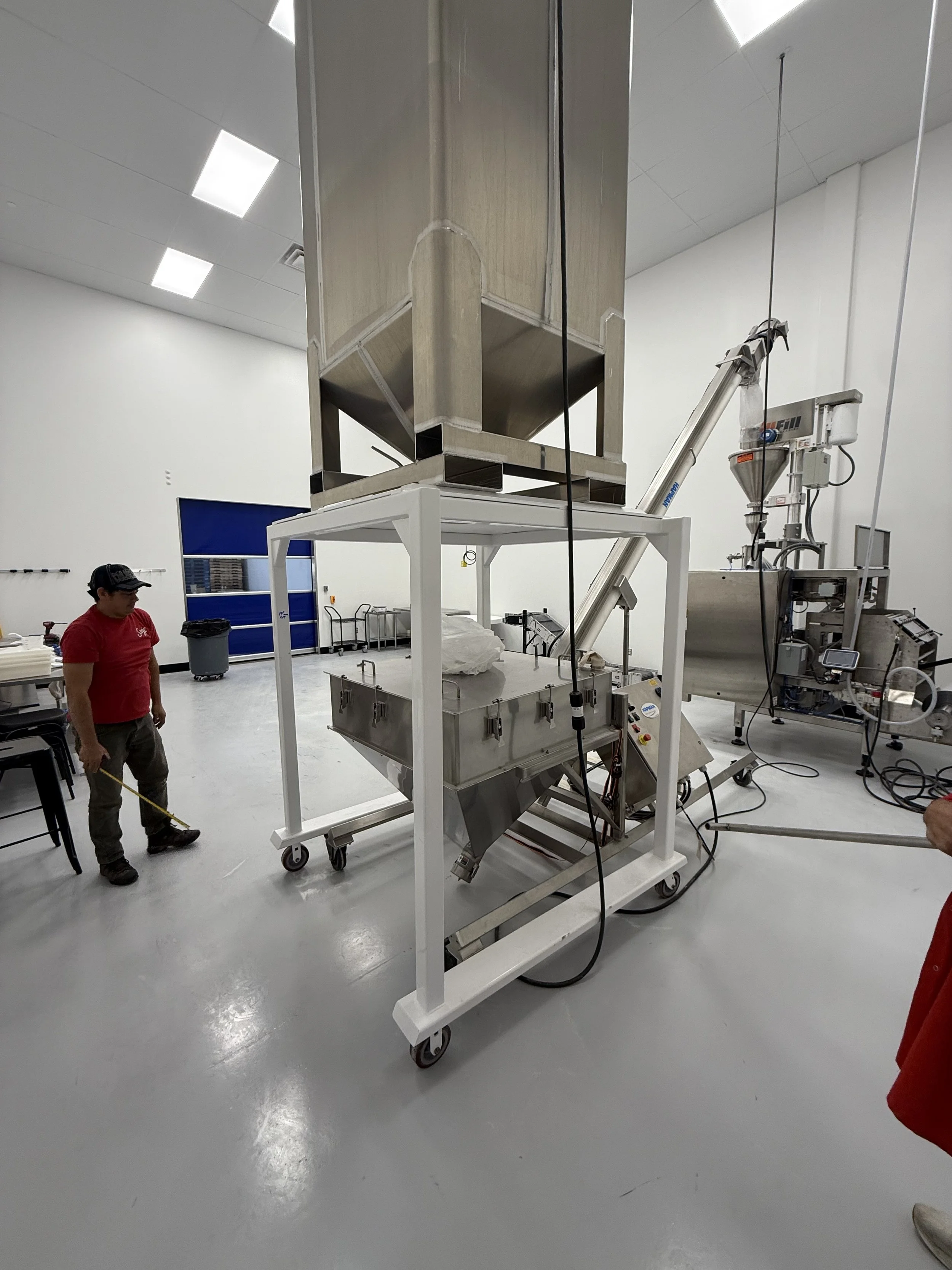 Industrial food processing machinery in a clean facility, with two workers present.