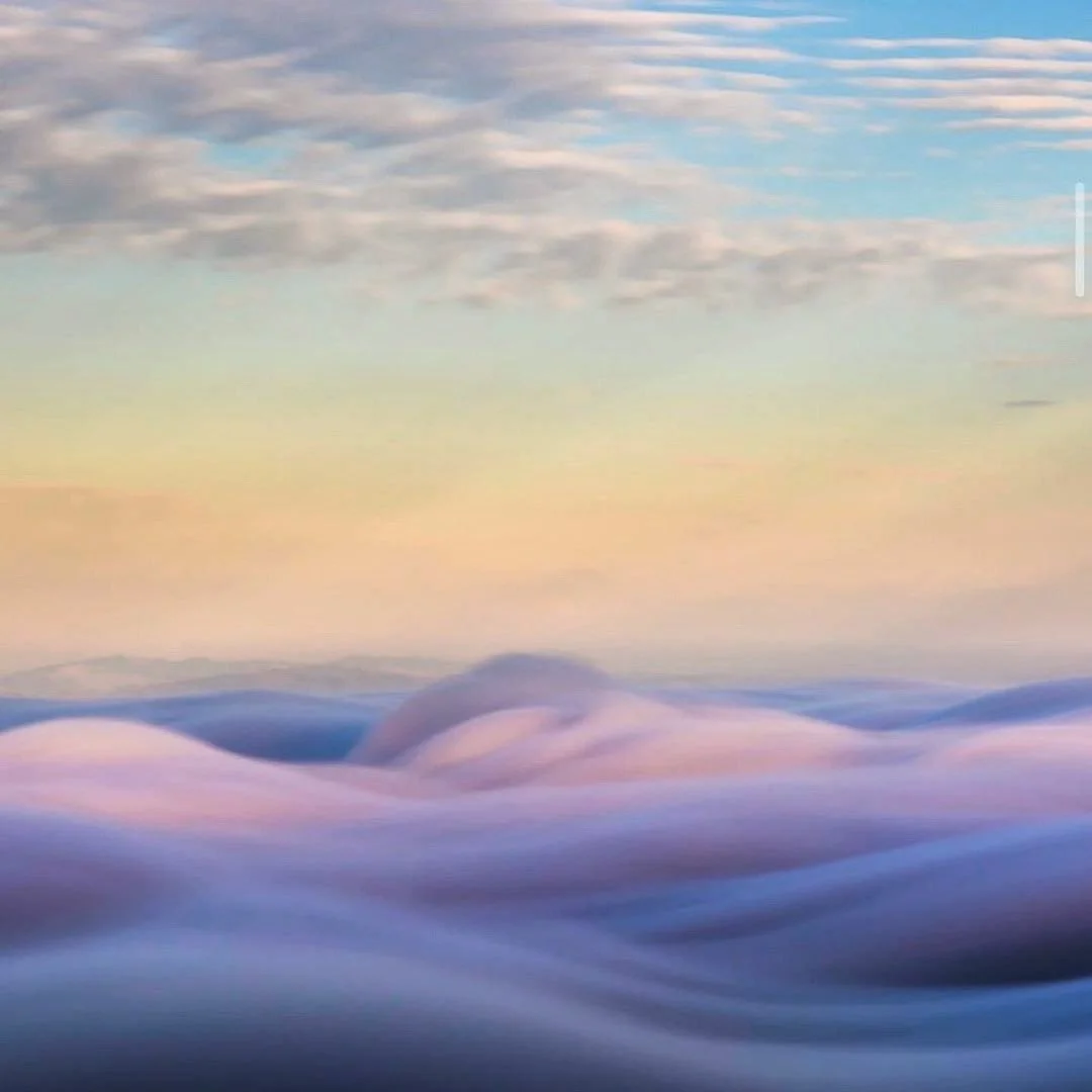 A digital painting of purple and pink clouds over distant mountains under a pastel-colored sky.