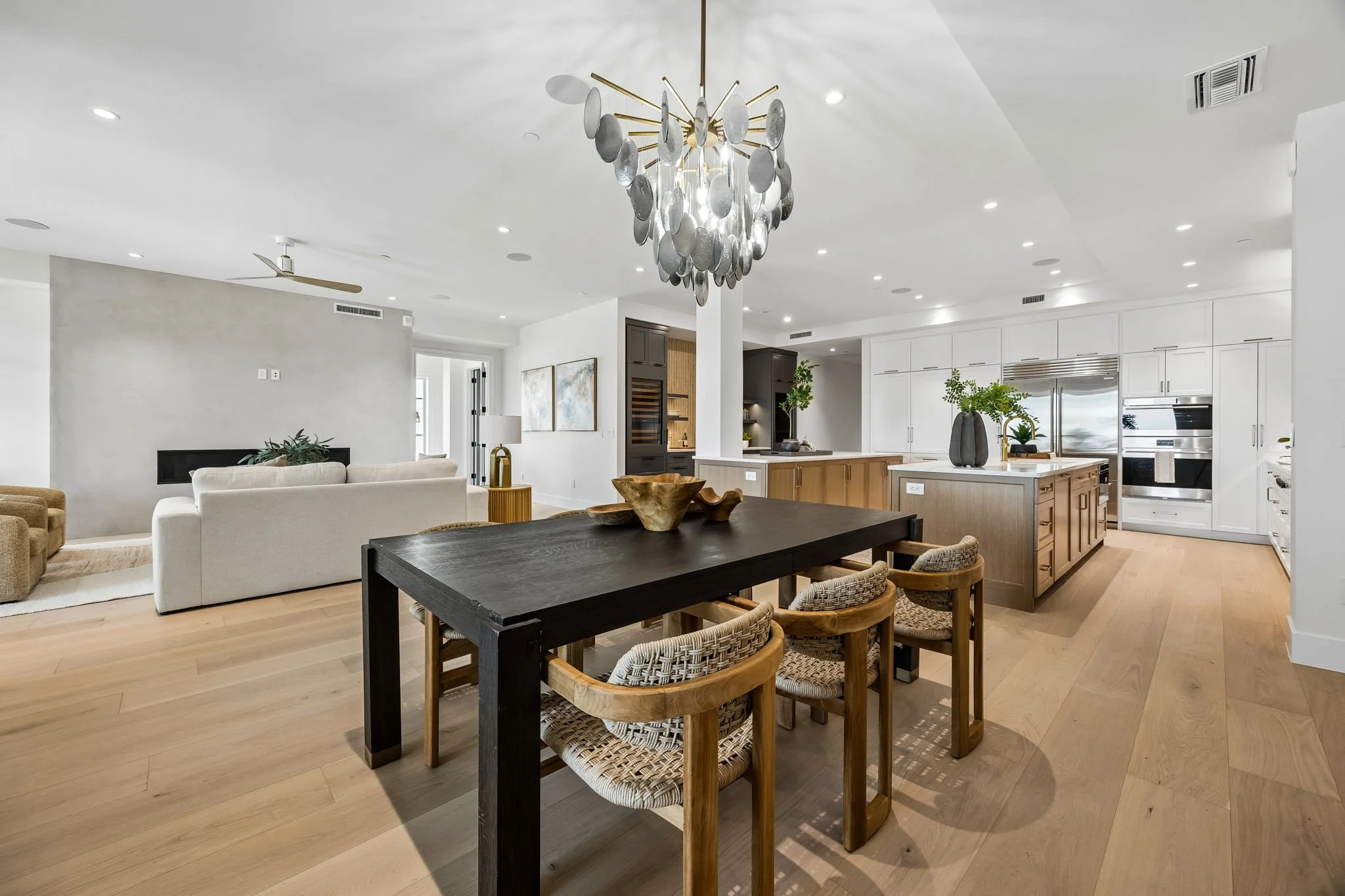 Open-concept living and kitchen area with light hardwood floors, white walls, modern furniture, and decorative accents.