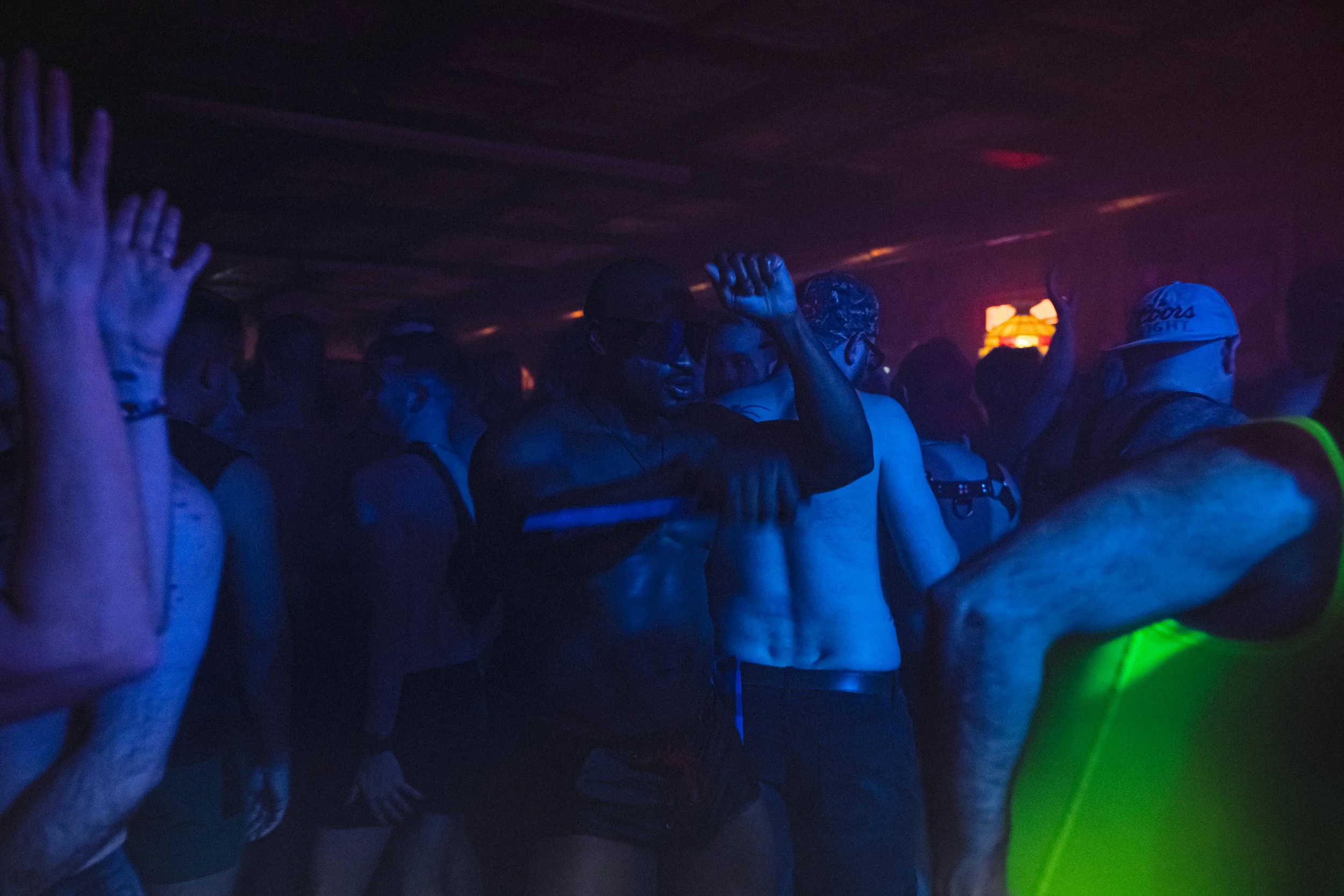 People dancing at a party or club in low light with colorful illumination.