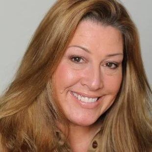 Close-up of a smiling woman with long, light brown hair and fair skin.