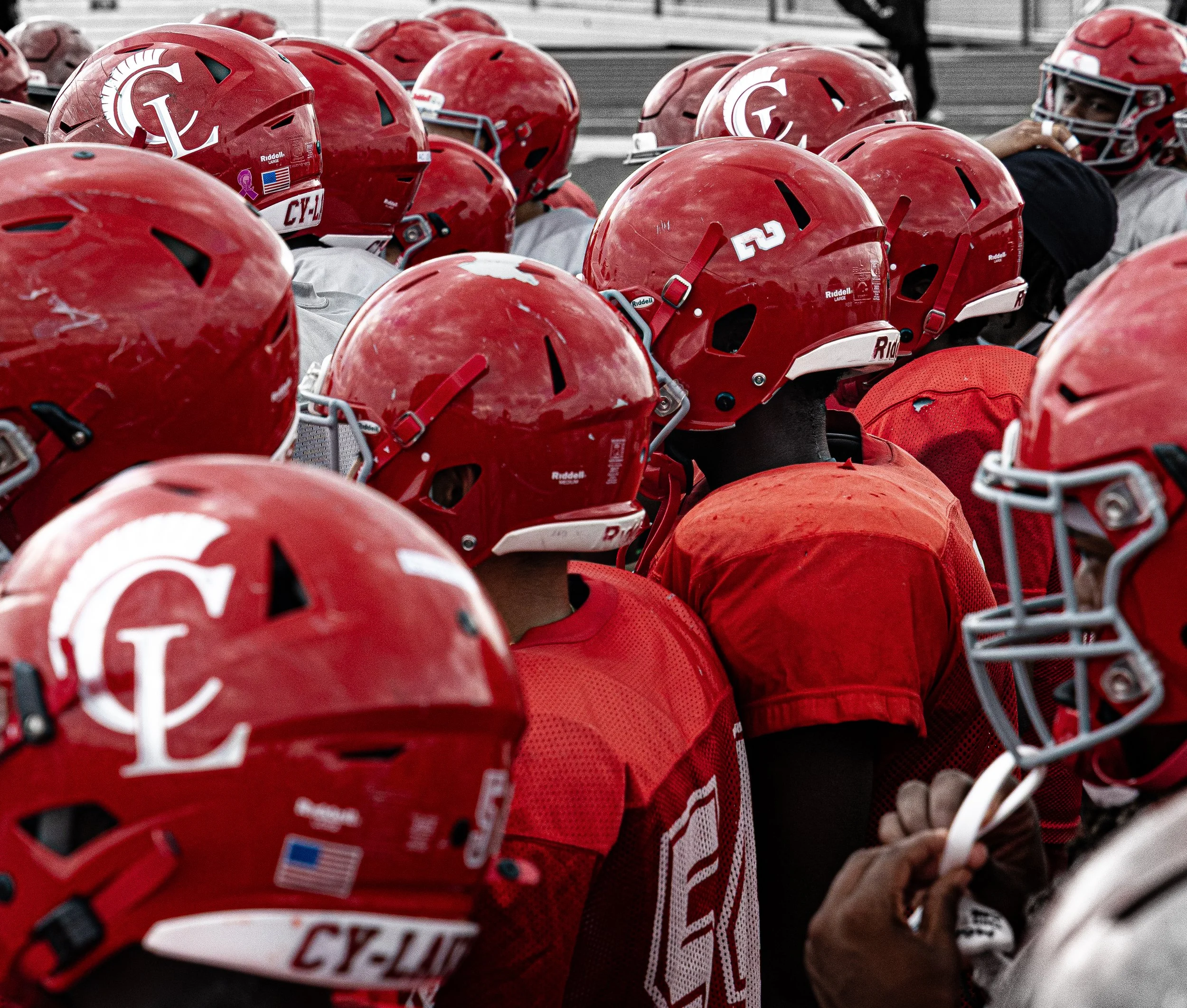 A group of football players in red helmets and jerseys huddled together on the field.