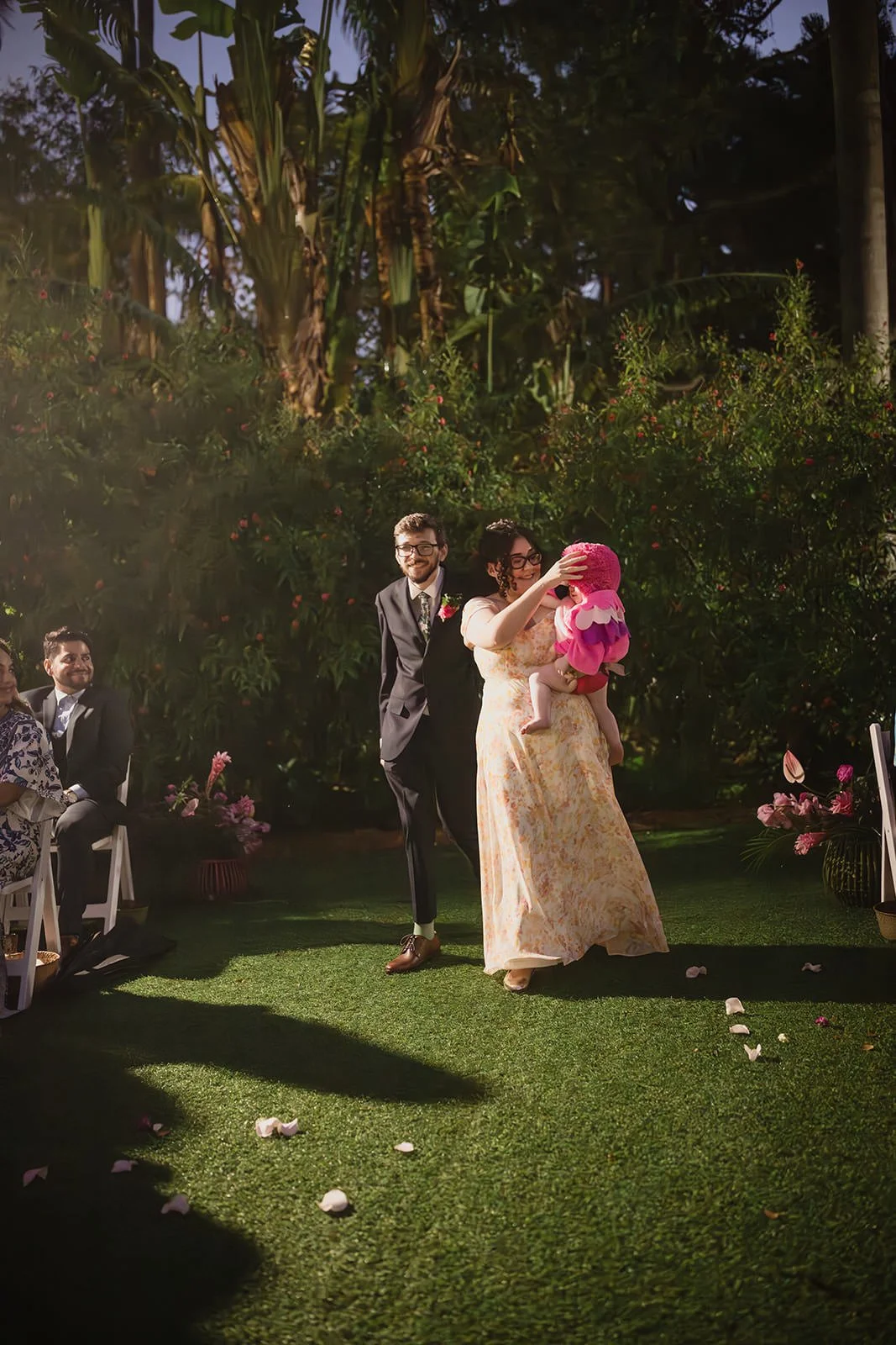 Marissa holding a small child as she walks down the aisle with her partner