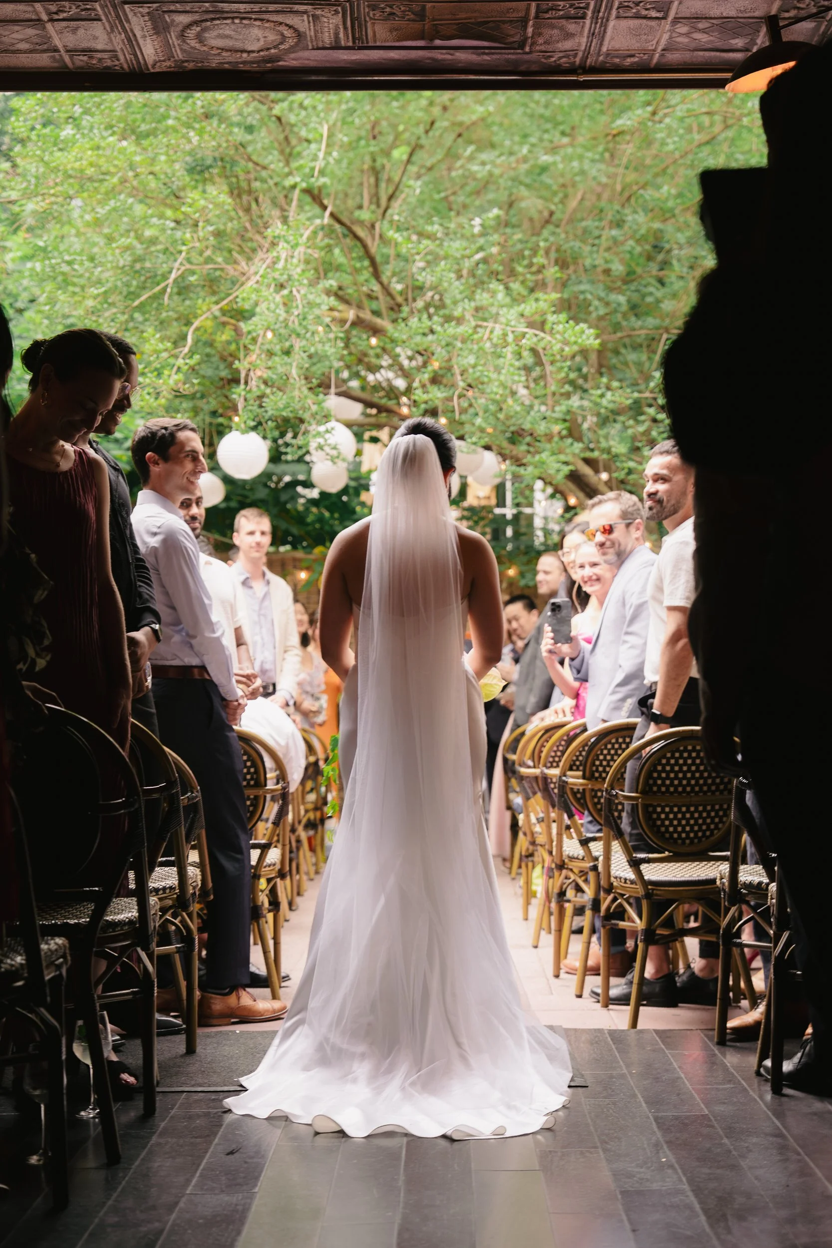 The back of a person in a wedding dress walking down the aisle