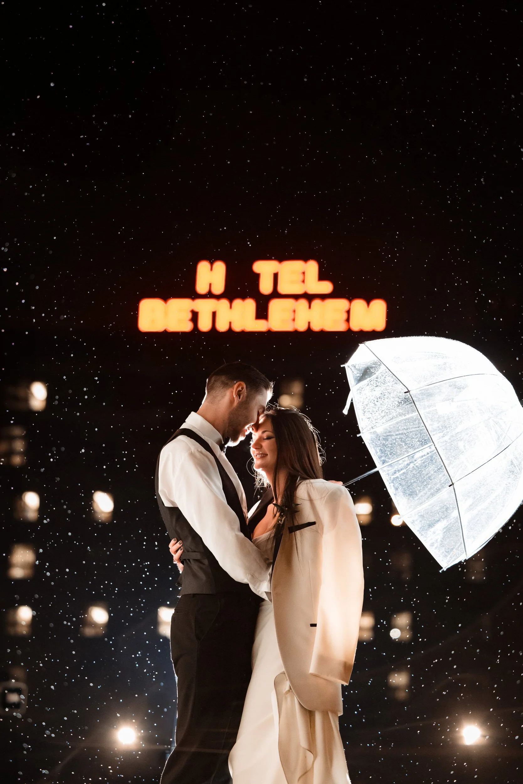 A newlywed couple about to kiss as one holds a clear umbrella