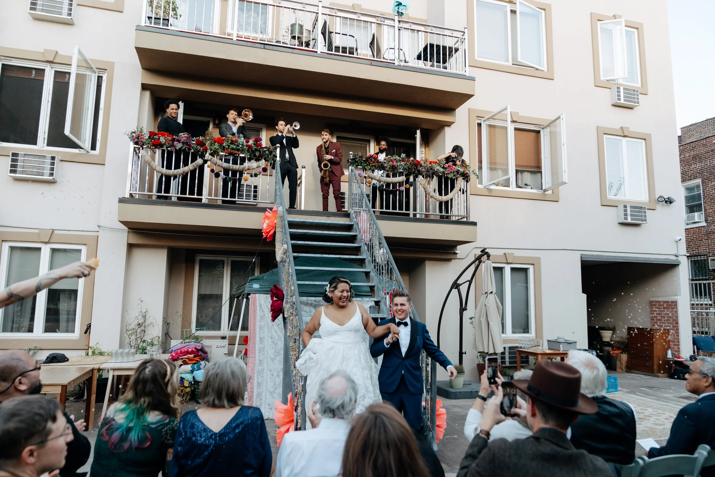 Wedding guests cheering as a newlywed couple walks down a staircase together
