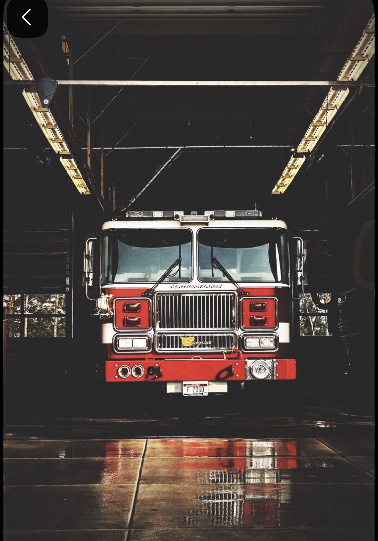 Front view of a fire truck parked inside a fire station garage.