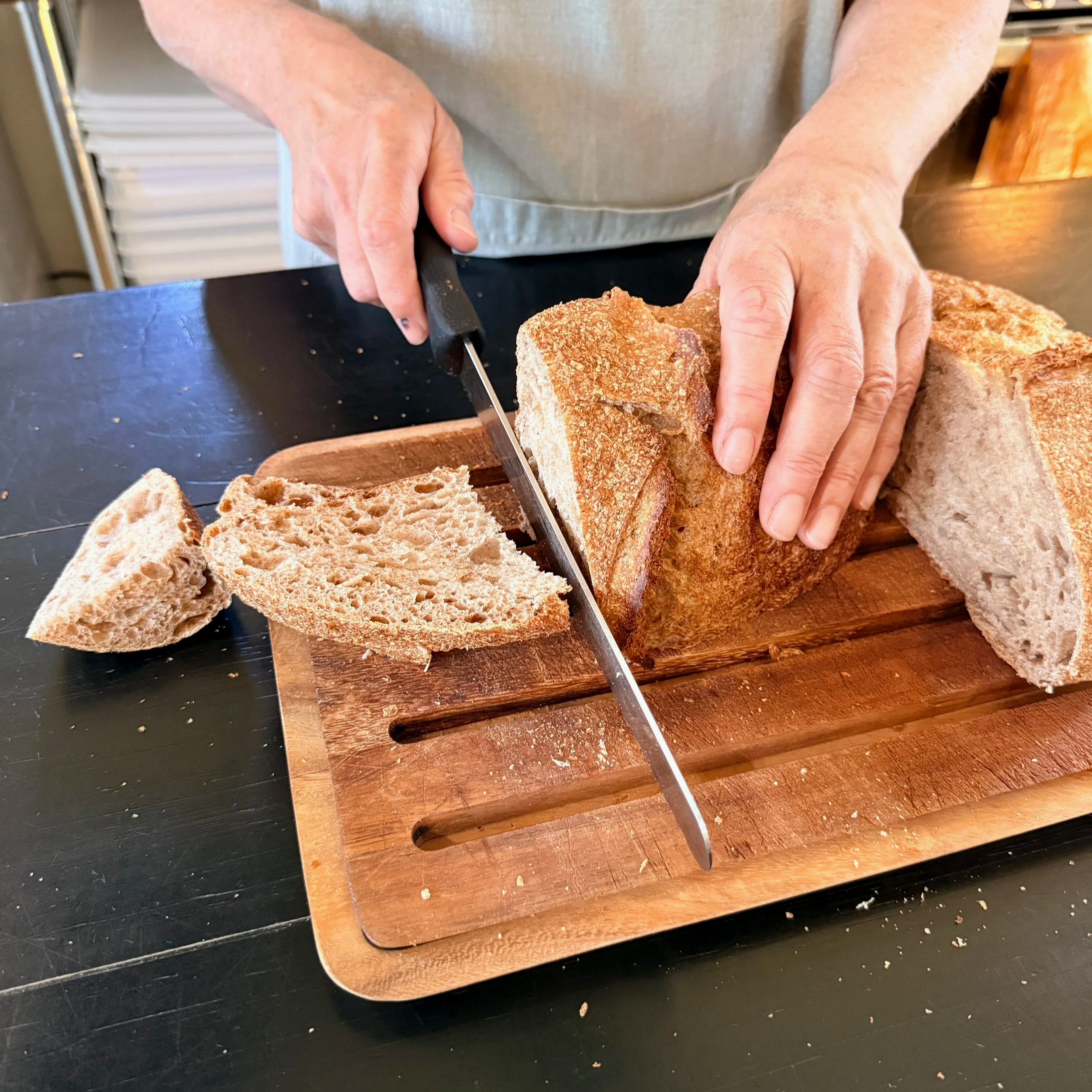 An easy way to slice sourdough bread is to cut it in half first. Then turn one half with the cut side down and slice.