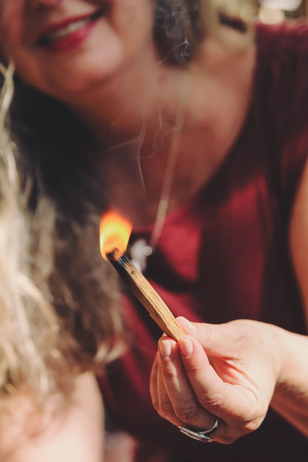 A woman is lighting a tattoo needle with a flame from a match, with a focus on the match and tattoo needle.