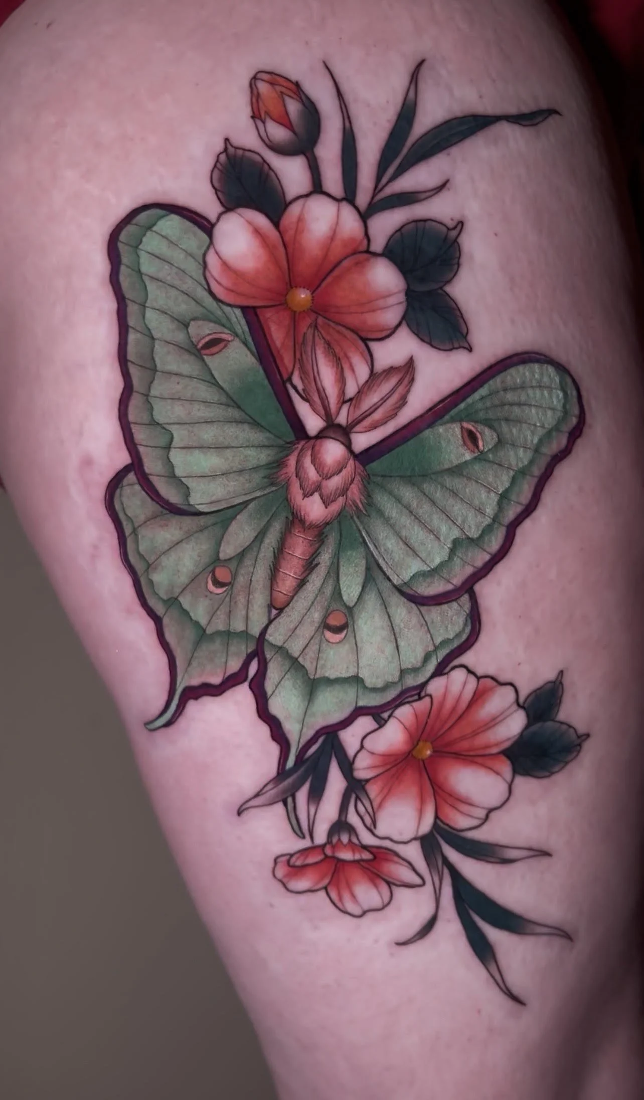 Colorful tattoo of a butterfly with floral accents on skin.